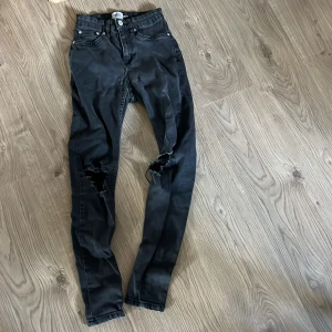 Svarta skinny jeans med slitningar - Svarta skinny jeans från Levi's med klassisk femficksdesign och slitningar vid knäna för en edgy look. Hög midja och smal passform som sitter tajt längs benen. Perfekta för dig som gillar en tuff och trendig stil.