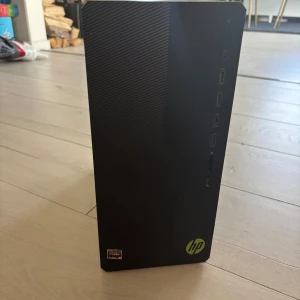 Dator  - Bilderna visar en stationär HP Pavilion Gaming Desktop PC, modell TG01-2829no, med AMD Ryzen-processor. Den har flera USB-portar, ljudutgångar och kortläsare på framsidan samt bra kylning och anslutningsmöjligheter på baksidan. Perfekt för gaming, studier eller kreativa projekt.
