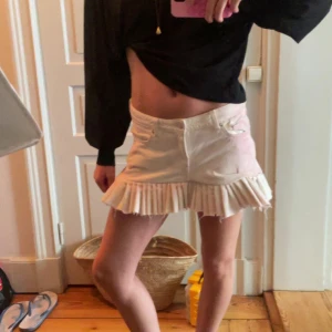 Vit jeanskjol med volangkant - Supersöt omsydd vit kort jeanskjol med bred volangkant nertill. De är originellt ett par vita och rosa jeans från weekday. Kjolen har klassiska jeansdetaljer som fickor fram och bak, Perfekt för dig som vill ha en unik och trendig look i sommar!!