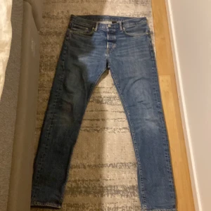 Blå slim jeans från HM - Säljer ett par klassiska blå skinny jeans från Levis. Jeansen har fem fickor, normal midja och är tillverkade i slitstarkt denim. Perfekta för dig som gillar en smal passform och tidlös stil.