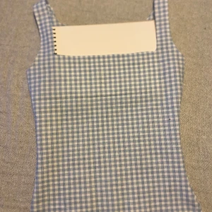 Blåvit rutig linnetopp - Supersöt ärmlös topp med blåvitt rutigt mönster och raka axelband. Toppen har en klassisk, lite 90-talsinspirerad look och är sydd i ett lätt och svalt tyg som passar perfekt till varma sommardagar. Hade papper bakom så att men skulle kunna de ringningen. Egen designad 