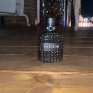 Valentino parfym svart nitar - Snygg parfymflaska från Valentino i svart glas med coolt nitat mönster och svart kork. Flaskan har en lyxig och edgy vibe med röda text på etiketten. Perfekt för dig som gillar statement-detaljer på sminkbordet. Det är valentino born in Roma och är 100ml. För en helt ny i affär kostar den ca 1100kr men jag säljer för bara 849kr