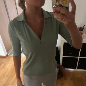 Ribbad grön pikétröja från Lindex - Snygg ljusgrön ribbad pikétröja från Lindex i storlek M. Tröjan har v-ringning, krage och trekvartsärm.