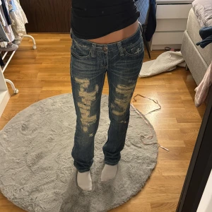Lågmidjade jeans med slitningar  - Super snygga unika jeans med slitningar skulle uppskatta till storlek 34, midjemått 34 och innerbenslängden 83. Jag är 170. Märket är blessed & cursed 