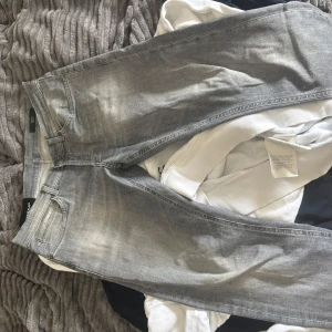 Grå jeans från Dondup, storlek 34 - Snygga grå jeans från Dondup i klassisk femficksmodell. Jeansen har en tvättad look med ljusare partier och raka ben. Tillverkade i mjukt denimtyg med Dondup-logga på knappen och bakfickan. Perfekta för dig som gillar stilrena och moderna jeans.
