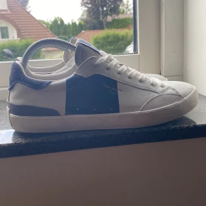 Helt nya Pepe jeans skor! - Snygga sneakers från Pepe Jeans i vitt och marinblått med klassisk låg profil. Skorna har snörning, rund tå och detaljer i mocka och skinn. Perfekta för en stilren och avslappnad look. Pepe Jeans-logga på plösen och sidan.