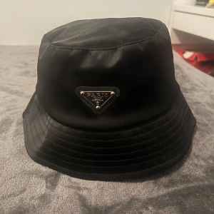 Prada hatt - Säljer min Prada-hatt i mycket fint skick. Den är sparsamt använd och ser nästan ny ut. Inga skador, fläckar eller tecken på slitage Den är i storlek M men kan även användas som storlek S
