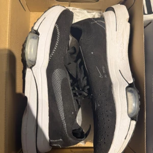 Nike svartvita sneakers med synlig dämpning - Svarta Nike sneakers med vit sula och synlig dämpning i hälen. Ovandelen är perforerad och har stickade detaljer samt en vitprickig Swoosh på sidan. Skorna har snörning och sportig vibe, perfekta för dig som gillar streetstyle och komfort.