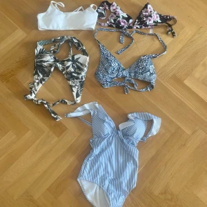 OANVÄNDA!! Flera bikinis & baddräkt i olika mönster - Säljer ett paket med fem snygga bikinidelar och en baddräkt. Inkluderar en vit sportig bikiniöverdel, en svart bikini med rosa blommor, en blåvit mönstrad bikini med knyt, en tropisk palm-mönstrad bikini och en blåvit randig baddräkt med volangdetalj. Perfekt för stranden eller poolen! 1 för 25kr alla 5 för 100kr