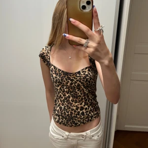 Leopardmönstrad topp - Säljer en leopardmönstrad topp med korta ärmar och snygg, lätt v-ringad urringning i storlek S.