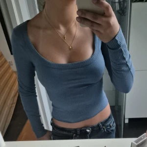 Blå ribbad långärmad topp - Säljer en blå ribbad långärmad topp från HM. Tröjan har en snygg croppad passform och en djup, rundad urringning.