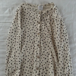 Blommig ribbad kofta från Zara - Supersöt ribbad kofta från Zara i beige med små svarta blommor 💐 Köpte den på Zara i Paris för några år sen men har tyvärr växt ut den 🥲Knappt använd, som ny! Kontakta vid önskat köp 🥰