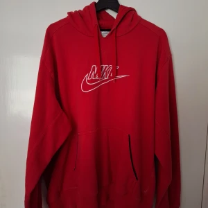 Röd Nike hoodie XXL - Snygg röd hoodie från Nike i storlek XXL med klassisk vit logga framtill. Hoodien har huva med snörning och en stor känguruficka. Perfekt för dig som gillar en loose och bekväm stil. Materialet är mjuk bomullsmix som känns skön mot huden.