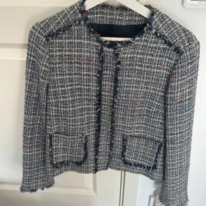 Tweedjacka från Zara  - Snygg  tweedjacka från Zara. Jackan har fransiga kanter, två fickor framtill och är tillverkad i ett grovt, vävt material som ger en cool och trendig look. 