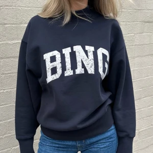  Anine Bing tröja - Cool sweatshirt från Anine Bing med stort vitt BING-tryck framtill. Tröjan har en klassisk rund hals, ribbade muddar och är långärmad. Perfekt för en avslappnad och trendig look. Materialet är mjukt och skönt, troligtvis bomullsmix.