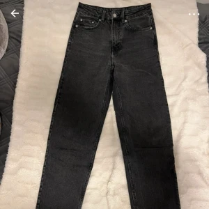 Svarta mom jeans från Weekday W26 L30 - Säljer ett par svarta mom jeans från Weekday, modell Lash Extra High. Jeansen har extra hög midja, raka ben och klassisk femficksdesign. Tillverkade i svart denim med en något tvättad look. Perfekta för dig som gillar en avslappnad men snygg stil.