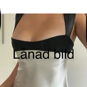 Svart och silver satinlinnetopp - Snygg linne-topp i satin  med breda svarta axelband och svart överdel, samt silvrig glansig nederdel. Toppen har en cool knyt-detalj i ryggen som ger extra stilpoäng. Perfekt för dig som gillar trendiga kontraster och vill sticka ut. Köpt här på Plick 