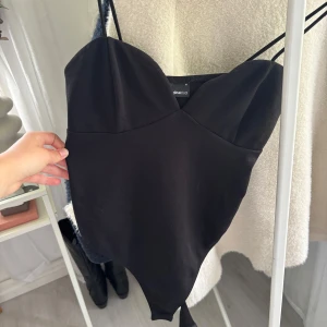 Body från Gina Tricot - Säljer en svart korsett-topp från Gina Tricot med smala axelband och hjärtformad urringning. Toppen har en figurnära passform och är perfekt för att skapa en snygg och stilren look. Materialet är mjukt och stretchigt för extra komfort. Storlek M, men passar S-L!❣️