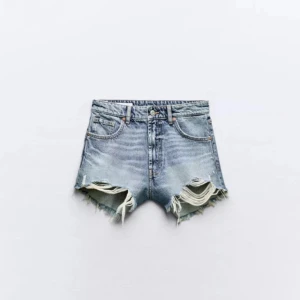 Zara jeans shorts  - Snygga högmidjade jeansshorts från Zara i klassisk blå denim. Shortsen har råa, fransiga kanter och slitna detaljer framtill för en cool, avslappnad vibe. Femficksmodell med dragkedja och knapp. Perfekta till sommaren och festivaler! Endast använda några gånger så nästan nyskick och inga defekter. Skriv gärna om ni har frågor eller vill ha mer bilder! 🥰