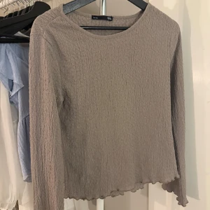 Grå långärmad topp från lager 157 - Säljer en stilren grå långärmad topp från märket lager 157. Toppen har en texturerad yta och en enkel rund halsringning. Perfekt för en avslappnad look. Passar bra till jeans eller kjol! 🤎