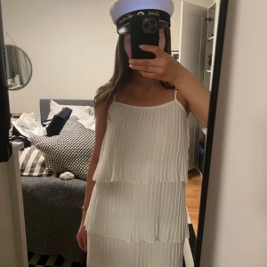 Vit plisserad klänning, studentklänning  - Säljer en söt vit plisserad klänning med smala axelband. Klänningen har flera lager som ger en fin volangeffekt. Perfekt för sommarens alla tillfällen och studenten!🌸🎓