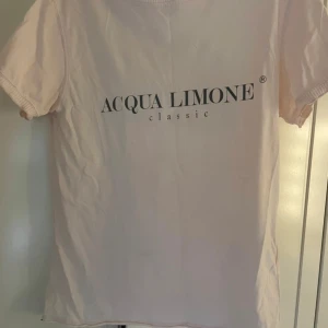 Ljusrosa t-shirt från Acqua Limone - Säljer en ljusrosa t-shirt från Acqua Limone med tryck både fram och bak. T-shirten har korta ärmar och en rund halsringning med märkets namn på insidan. Perfekt för en avslappnad stil.