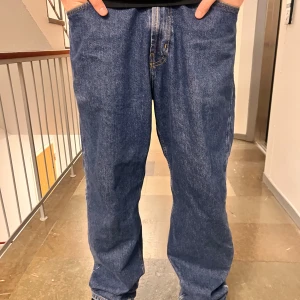 Blå jeansbyxor från JunkYard st M - Snygga blå jeansbyxor från Junkyard med en klassisk femficksdesign. Byxorna har en rak passform och är tillverkade i slitstarkt denim. Använda fåtal gånger då det inte passar mig så bra. Nypris 700kr 