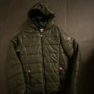 Svart quiltad jacka från Colmar - Säljer en snygg grön jacka från Colmar med huva och dragkedja. Jackan har ett stilrent märke på ärmen och i använt skick. Pris kan diskuteras.
