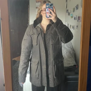 Olivgrön jacka - Detta är en ordentlig ”oljerock” i väldigt bra skick. Den är tjock och bra för alla väder och tillfällen. Märket är kännt för sina hållbara plagg och det syns!(Detta har inte varit min och sitter därför stort på mig)