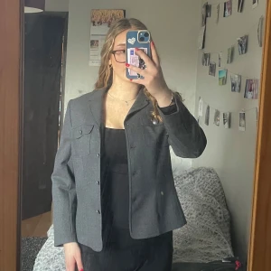 Grå kavaj/jacka - Snygg grå kavaj med klassisk kort design och knappar framtill. Märket använder kvalitetsmaterial och det syns då där inte är några tecken på användning. Kan användas som kavaj eller jacka.