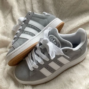 Adidas campus 00s - Säljer mina adidas campus 00 i färgen grå! Första bilden lånad, vill även nämna att jag har bytt ut snörena då jag tycker att det är snyggare med tjockare snöre. Om man vill ha med orginalsnöre kan jag skicka med dem! ❤️väldigt fint skick, sällan använda.