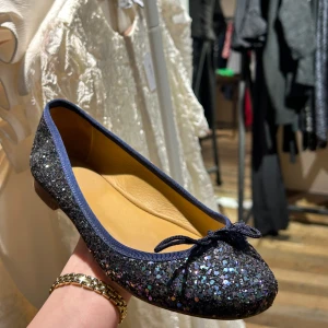 Glittriga ballerinaskor med rosett - Nypris: ca 2100kr. Snygga glittriga ballerinaskor i mörkblått med en söt rosett på tån. Perfekta för att lägga till lite extra bling till din outfit. Skorna har en bekväm passform och är lätta att bära hela dagen.