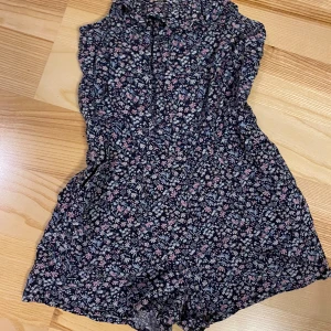 H&M flerfärgad playsuit, storlek 140 - Söt, blommig playsuit med smala axelband och resår i midjan. Perfekt för sommaren!