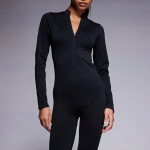 Svart långärmad jumpsuit - Snygg och stilren svart jumpsuit med lång ärm och dragkedja framtill. Aldrig använd 