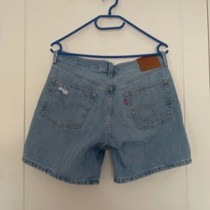 Blå jeansshorts från Levi's - Snygga blå jeansshorts från Levi's med en klassisk design. De har en knappgylf och slitna detaljer för en trendig look. Perfekta för en avslappnad stil. Säljs till högsta bud!
