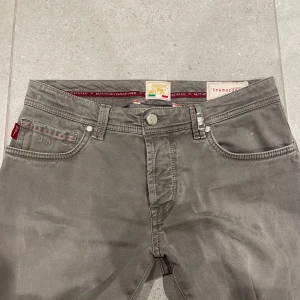 Grå byxor från Tramarossa - Unika grå byxor från Tramarossa med broderad detalj '1967' och knappar med unika mönster. Bästa kvaliteten jeans mässigt som går att få. Tillverkade för hand i Italien med en stilren design och slim passform ( 31W 34L). Bild på och mått finns vid intresse!