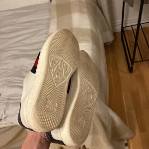 Gucci ace sneakers - Snygga vita sneakers från Gucci med klassiska ränder i rött och blått på sidan. Skorna har en stilren design med snörning och en diskret logga på hälen. Perfekta för en trendig look. JAG TAR BYTEN