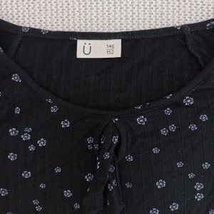 Svart blommig långärmad topp från Kappahl - Säljer en svart långärmad topp från Kappahl med små vita blommor. Storlek 146/152, passar XXS. Toppen har en knytning vid halsen och är perfekt för en stilren look. Passar bra till både jeans och kjol. 🌸