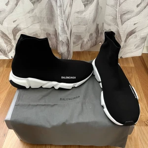 Balenciaga speedtrainers 2.0 STORLEK 43 - Snygga svarta sneakers från Balenciaga med en strumpliknande design och vit sula. Skorna har en modern och stilren look med Balenciaga-loggan på sidan. Perfekta för en trendig och bekväm stil.