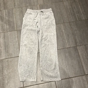 Grå mjukisbyxor från Juicy Couture - Säljer ett par grå mjukisbyxor från Juicy Couture. Byxorna har en bekväm passform med resår och snörning i midjan samt fickor både fram och bak. Perfekta för en avslappnad stil. Dom har en liten fläck på vänster ben. Priser är diskuterbart. 
