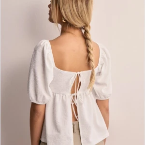 Vit blus med puffärmar - Säljer en fin vit blus med trekvartsärmar och knytning i ryggen. Tröjan är i storlek M och är från Gina Tricot. Den är använd endast en gång så skicket är som nytt!