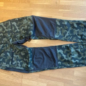 Camouflage byxor från High Mountain - Snygga camouflagebyxor från High Mountain med elastisk midja och flera praktiska fickor.        Lite använda