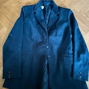 Tävlings kavaj  - Elegant marinblå kavaj med sammetskrage och knappar framtill. Perfekt för en stilren look. Kavajen har en klassisk passform och långa ärmar.