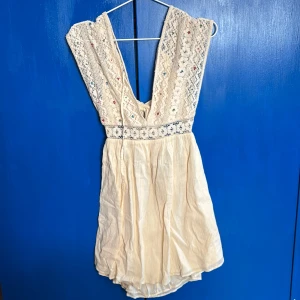 Beige klänning från Zara - Charmig beige klänning från Zara med vackra spetsdetaljer och broderier. Klänningen har en omlott-design och knytband i ryggen. Väldigt somrig och skön, lite boho möter stranden☀️💝🌊