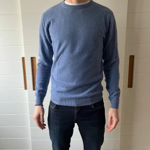 Blå kashmirtröja från John Henric - Säljer en stilren blå kashmirtröja från John Henric. Tröjan har en klassisk design med rund hals och långa ärmar, perfekt för en elegant och bekväm look. Passar utmärkt till både jeans och chinos.