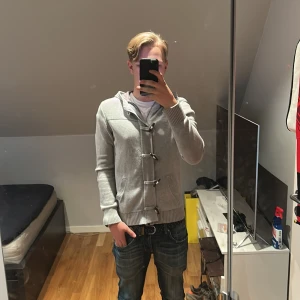 Grå stickad zip hoodie - Säljer en stilren grå hoodie från dress yourself med unika detaljer framtill och en praktisk huva. Perfekt för en avslappnad look.Lite kort på mig som är 183cm. Tröjan säljs inte längre!