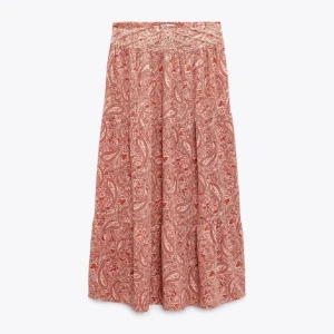 Zara maxi kjol - Säljer en vacker långkjol med paisleymönster i rött och beige. Kjolen har en bekväm passform och är perfekt för en bohemisk stil. Den är tillverkad i ett lätt och luftigt material som passar bra för varmare dagar.