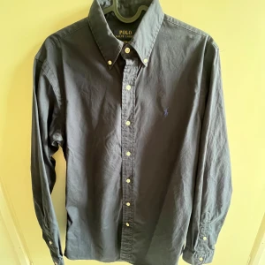 Marinblå skjorta från Ralph Lauren - Snygg Marinblå skjorta från Ralph Lauren i storlek S. Skjortan har långa ärmar och klassisk krage med knappar. Perfekt för en stilren look.