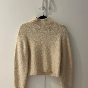 Beige stickad tröja från Zara - Säljer en mysig beige stickad tröja från Zara. Tröjan har en hög krage och långa ärmar, perfekt för kyligare dagar. 