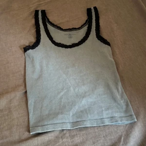 Grå linnetopp med spetsdetaljer - Säljer en grå linnetopp med svarta spetsdetaljer. Perfekt för lager-på-lager eller som den är. Passar till många olika stilar och tillfällen.